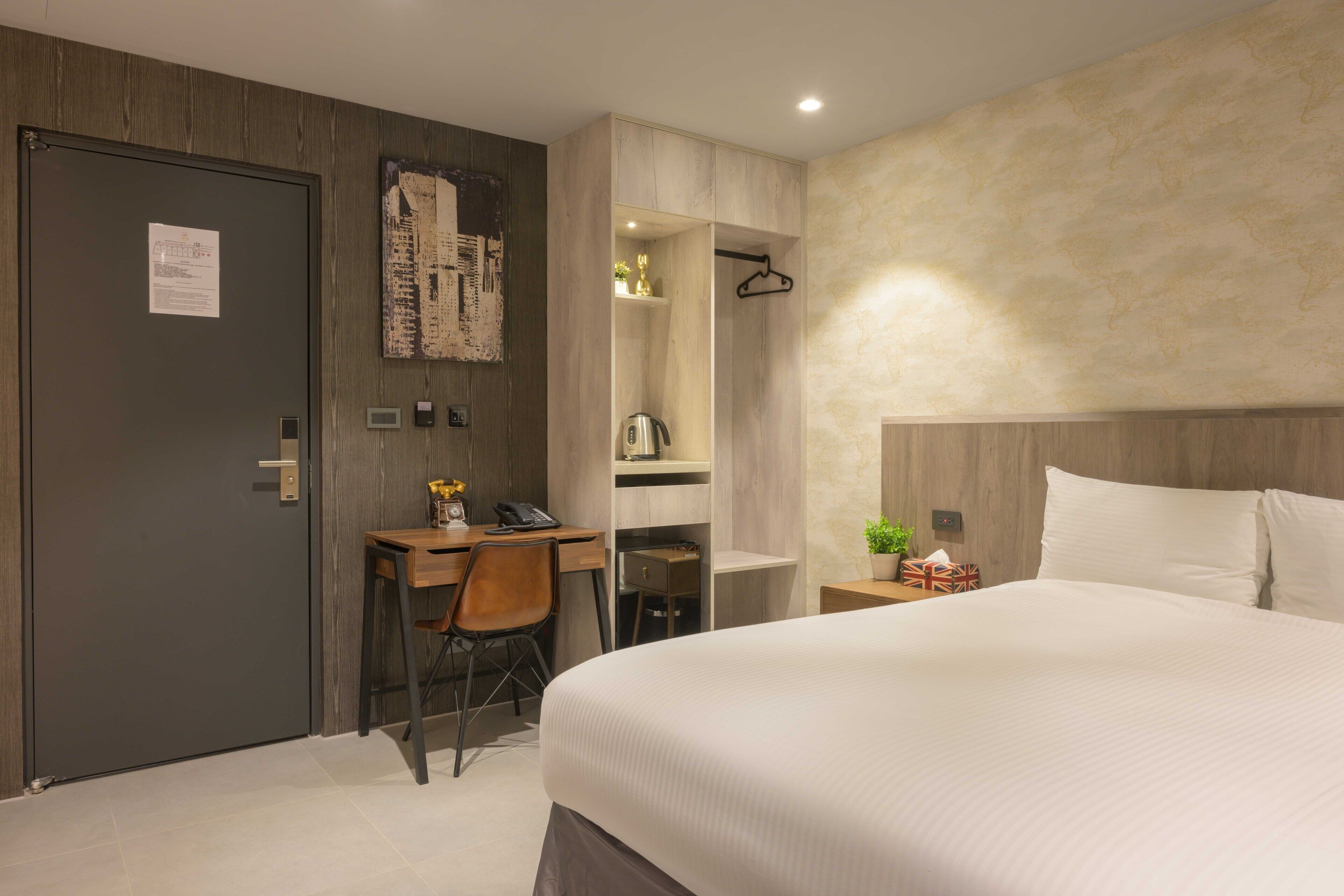 Habitación de hotel con cama, escritorio, silla y armario.