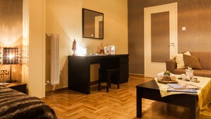 A room with a wooden floor, a desk with a chair, a sofa, a coffee table, and a mirror on the wall. - Spacious Safe Apartment Walk Acropolis (Athens)