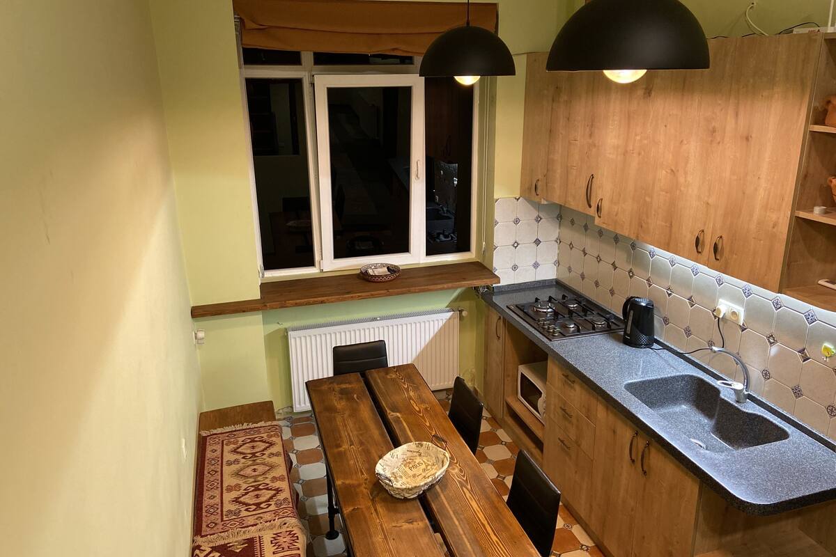 A compact kitchen with wooden cabinets, a built-in stove, and a window above the sink.
