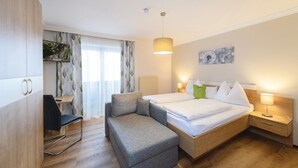 Et moderne hotelværelse med seng, sofa, skrivebord og fjernsyn på væggen.
