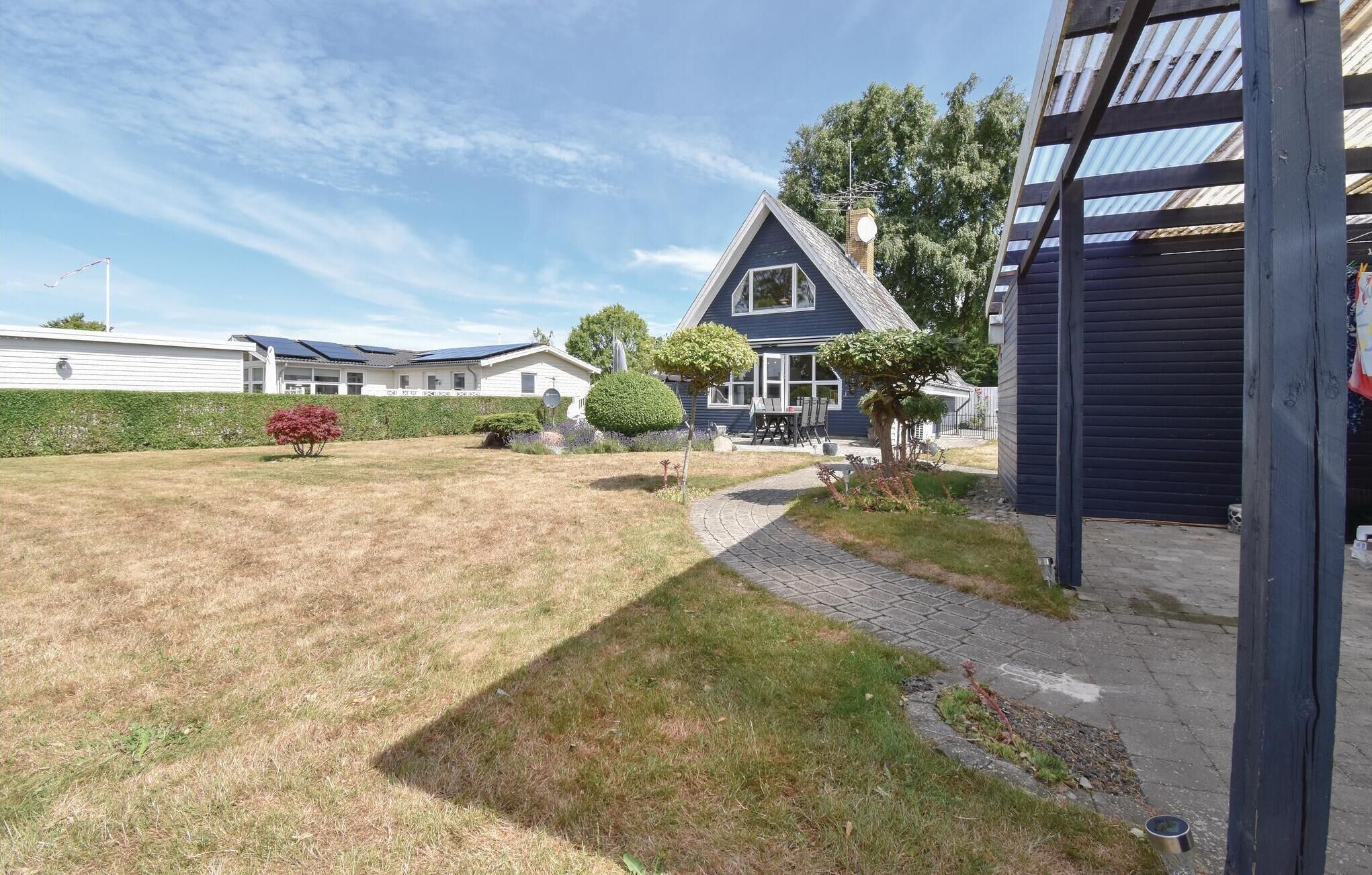A residential property with a well-maintained lawn, a paved pathway, and a small patio area with outdoor furniture.