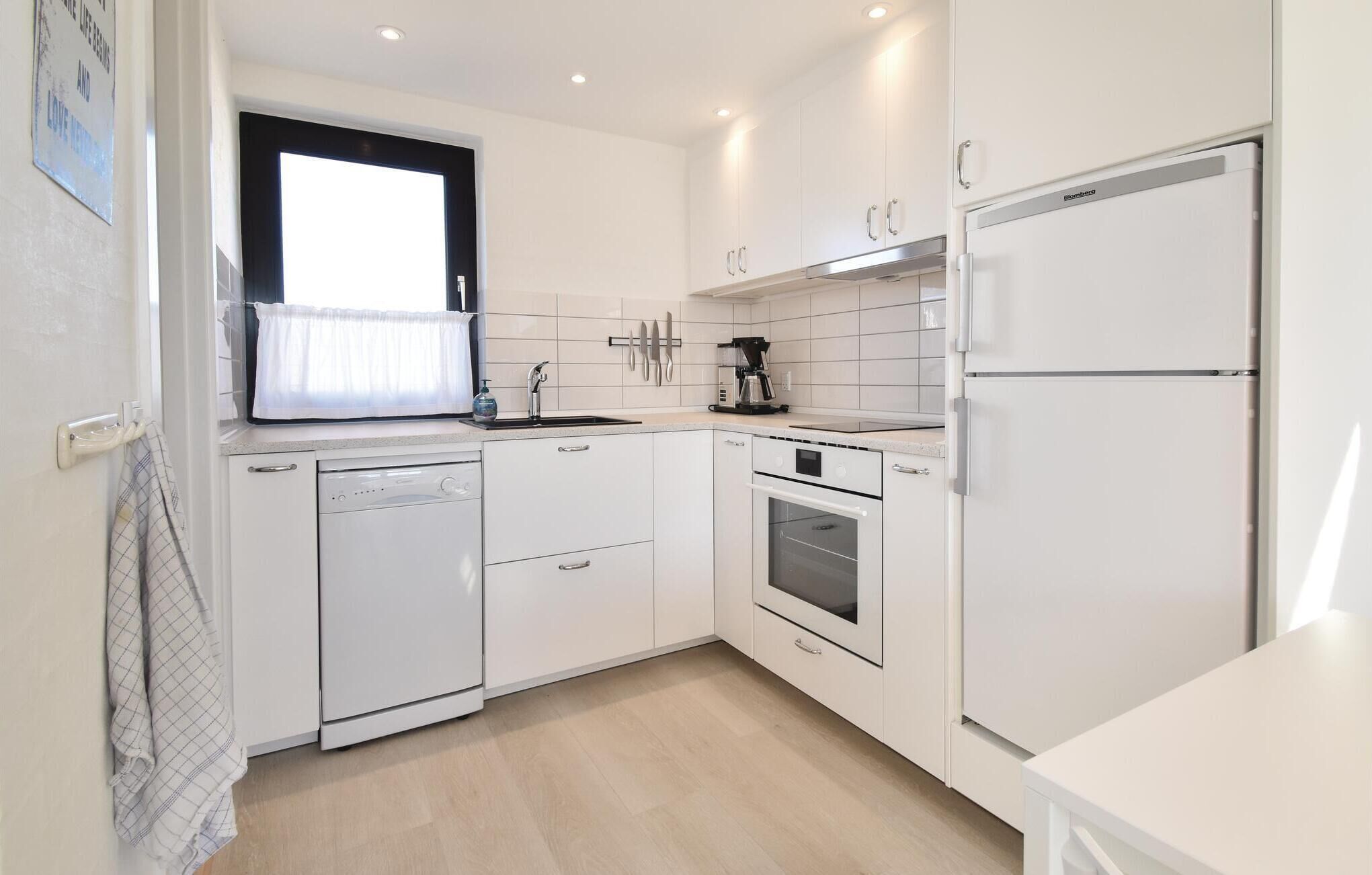 A modern kitchen with white cabinetry, a dishwasher, an oven, and a refrigerator.