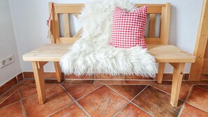Un banco de madera con un suave plaid blanco y una almohada de cuadros rojos y blancos.