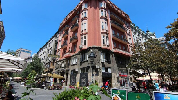 Un edificio a più piani con uno stile architettonico classico, caratterizzato da balconi e un ingresso centrale con un lampione.