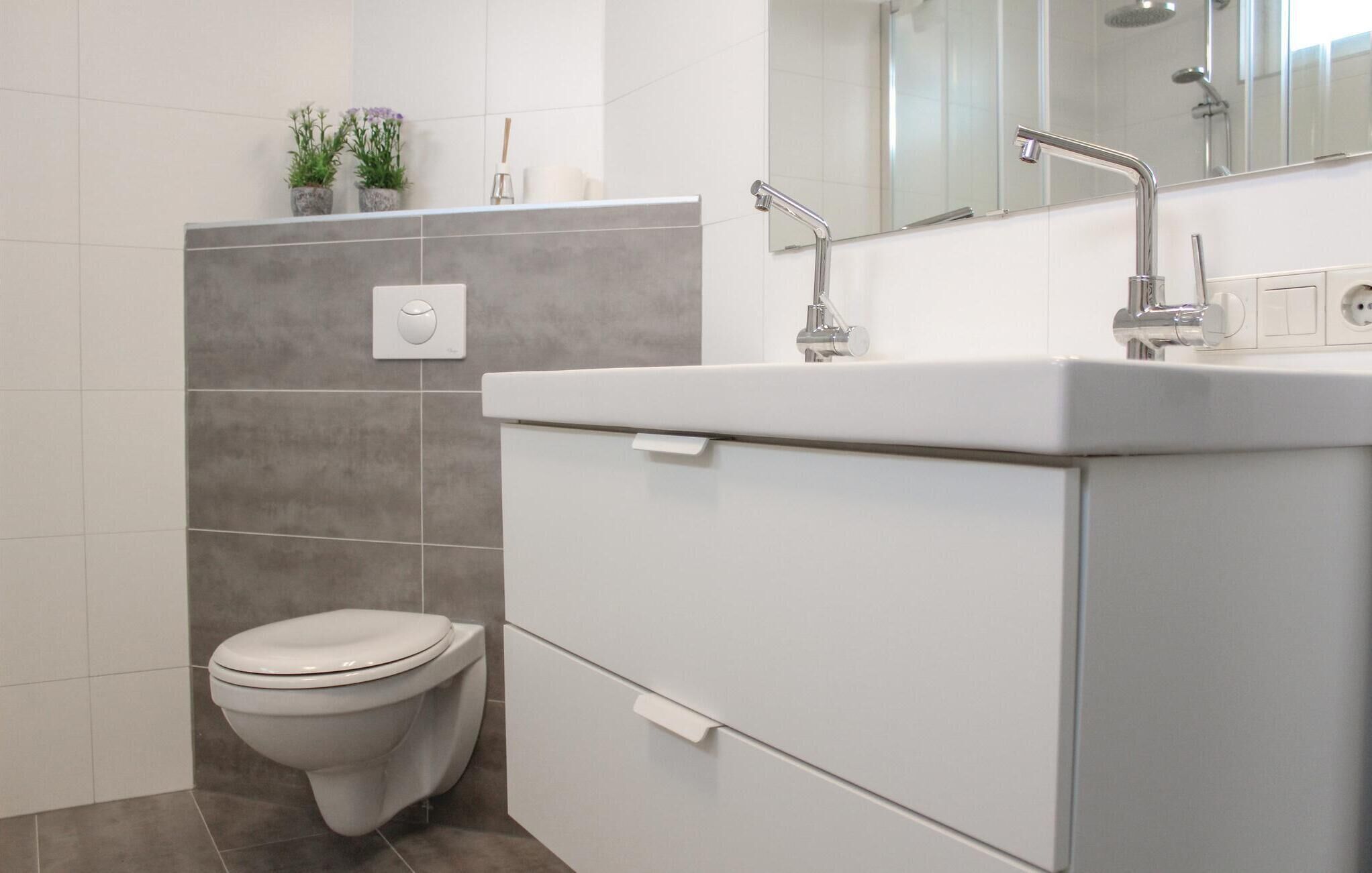 A modern bathroom with a toilet, a sink, and a shower.