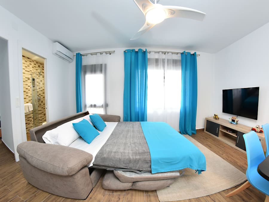Une chambre d’hôtel moderne équipée d’un lit, d’un canapé, d’une télévision et d’un bureau.