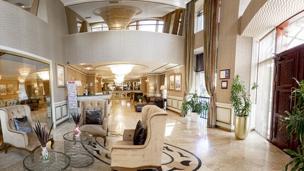 A spacious lobby with a high ceiling, a central seating area, and a bar. - Sapphire Inn (Baku)
