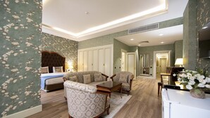 A modern hotel room with a bed, sofa, chairs, a dining table, and a kitchen area. - Sapphire Inn (Baku)
