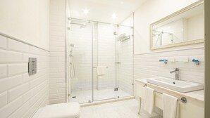 A modern bathroom with a glass-enclosed shower, a white toilet, and a sink with a mirror above it. - Sapphire Inn (Baku)