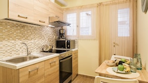 A compact kitchen with a sink, stove, microwave, and a dining area with a table set for two. - Central cozy apartment (Athens)