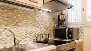 A modern kitchen with a stainless steel sink, a microwave, a coffee maker, and an oven. - Central cozy apartment (Athens)