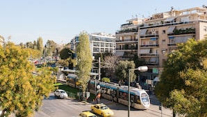 A modern urban street with a tram, cars, and multi-story buildings. - Central cozy apartment (Athens)