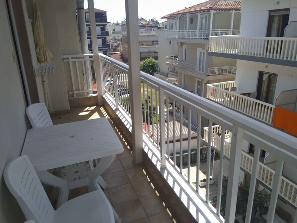 Un balcón con mesa y sillas, con vistas a una zona residencial con varios edificios.