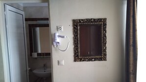 Una habitación pequeña con escritorio, silla y espejo de marco decorativo.