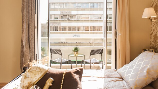 A hotel room with a balcony, a bed with pillows, a small table with chairs, and a lamp. - Central Apartment near Acropolis (Athens)