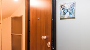 A wooden door with a silver handle, a doormat with the word "Welcome", and a painting of a blue butterfly on the wall. - Central Apartment near Acropolis (Athens)