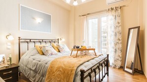 A bedroom with a bed, bedside table, lamp, and a window with curtains. - Central Apartment near Acropolis (Athens)