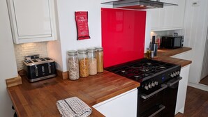 Et køkken med røde backsplash, en vintage toaster og krukker med korn.