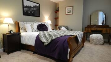 A bedroom with a bed, bedside tables, a dresser, a mirror, and a carpeted floor.