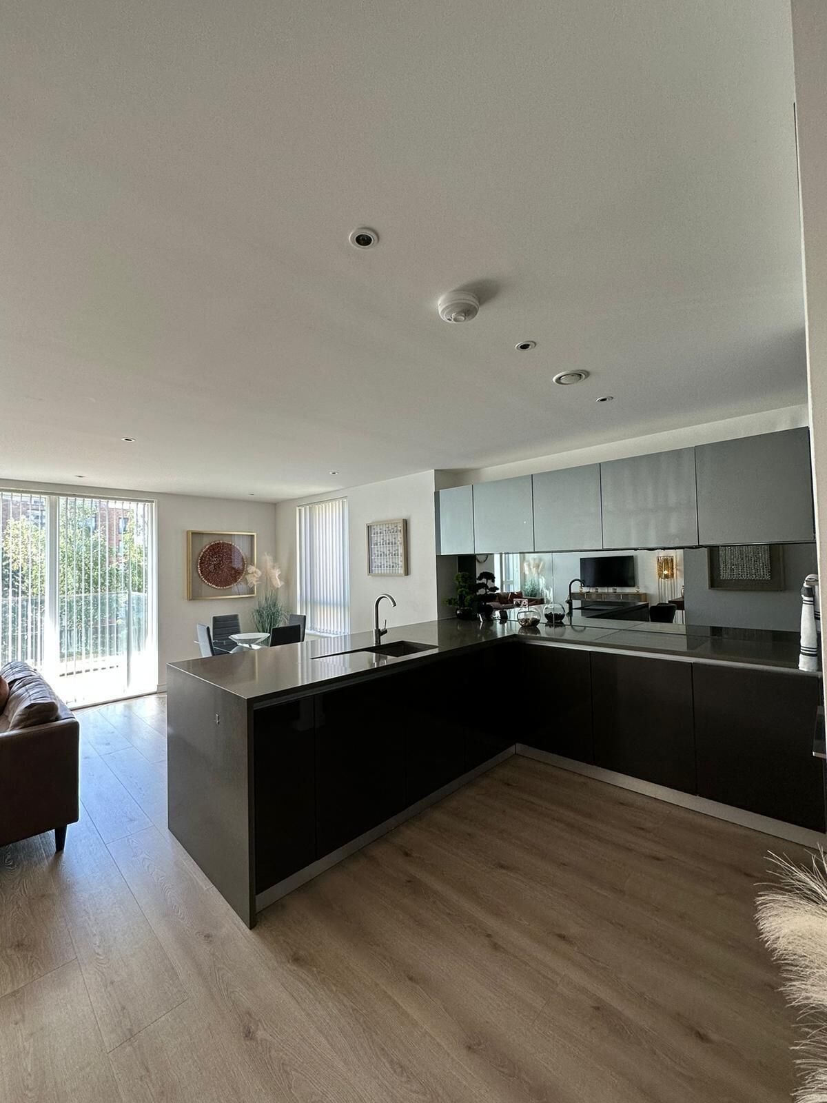 A modern kitchen with a large island, dark cabinetry, and a flat-screen TV.