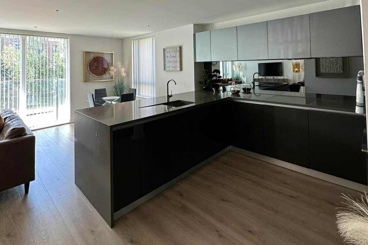 A modern kitchen with a large island, dark cabinetry, and a flat-screen TV.