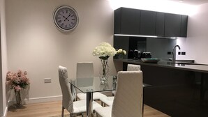 A modern kitchen with black cabinets, a glass dining table, and a white vase with flowers.
