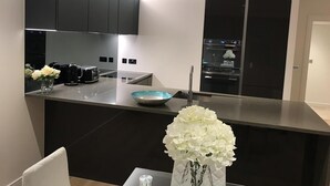 A modern kitchen with dark cabinetry, a central island, and a built-in oven.