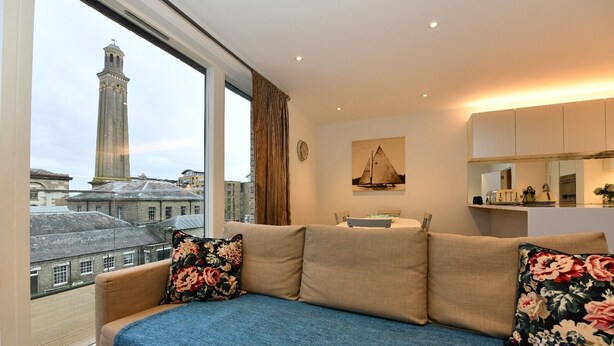 A modern living room with a sofa, a view of a cityscape, and a large window.