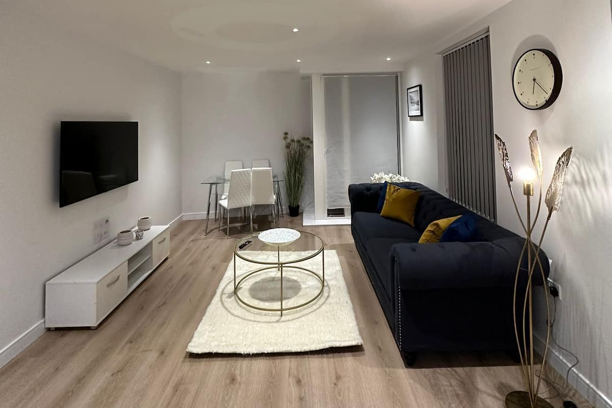A modern living room with a flat-screen TV, a round coffee table, a sofa, and a floor lamp.