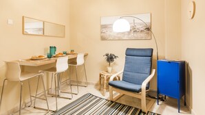 A small, modern room with a dining table, chairs, a blue armchair, a blue cabinet, and a painting on the wall. - Central Quiet Safe Apartment (Athens)