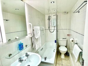 A bathroom with a sink, mirror, and shower. - Seafront Apartments (North Shields)