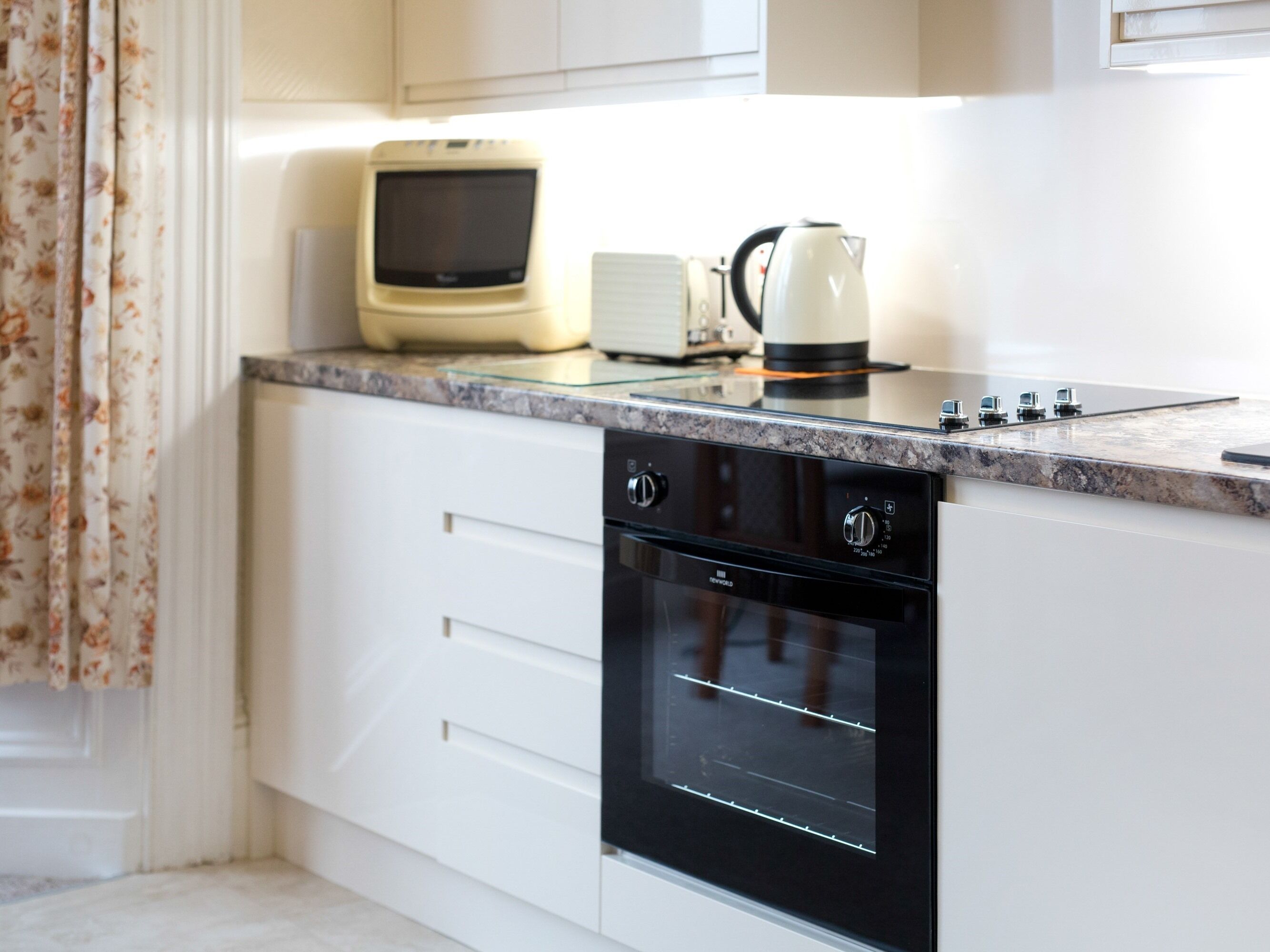 Una cocina moderna con armarios blancos, un horno negro y un microondas en la encimera.