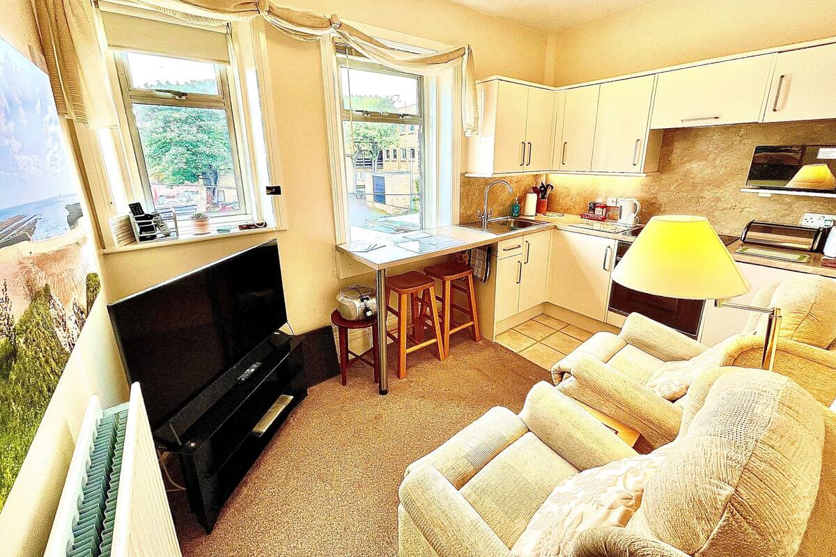 A compact living space with a kitchenette, a dining area, and a seating area with a television.