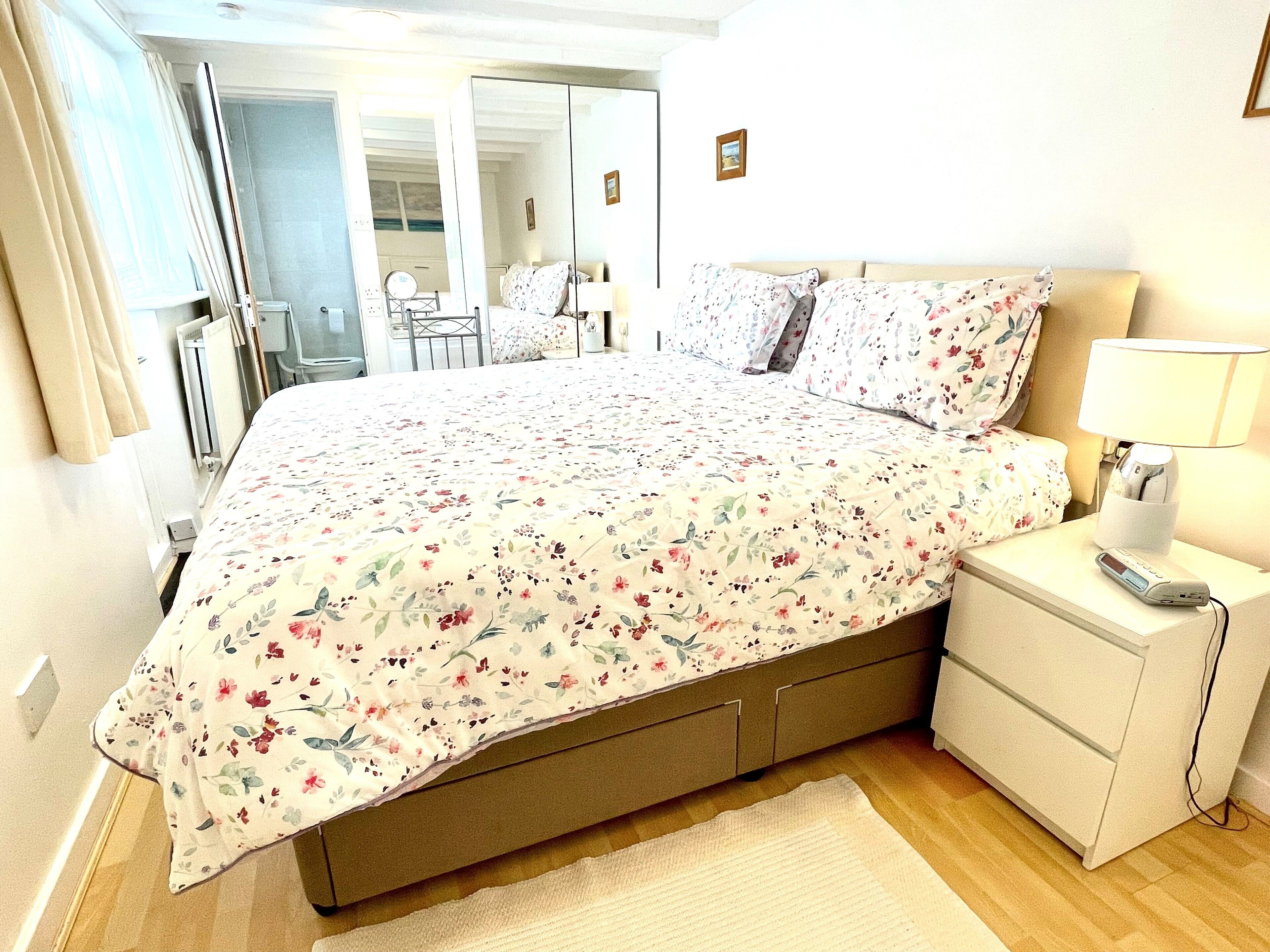 A bedroom with a bed, nightstand, and a mirror.