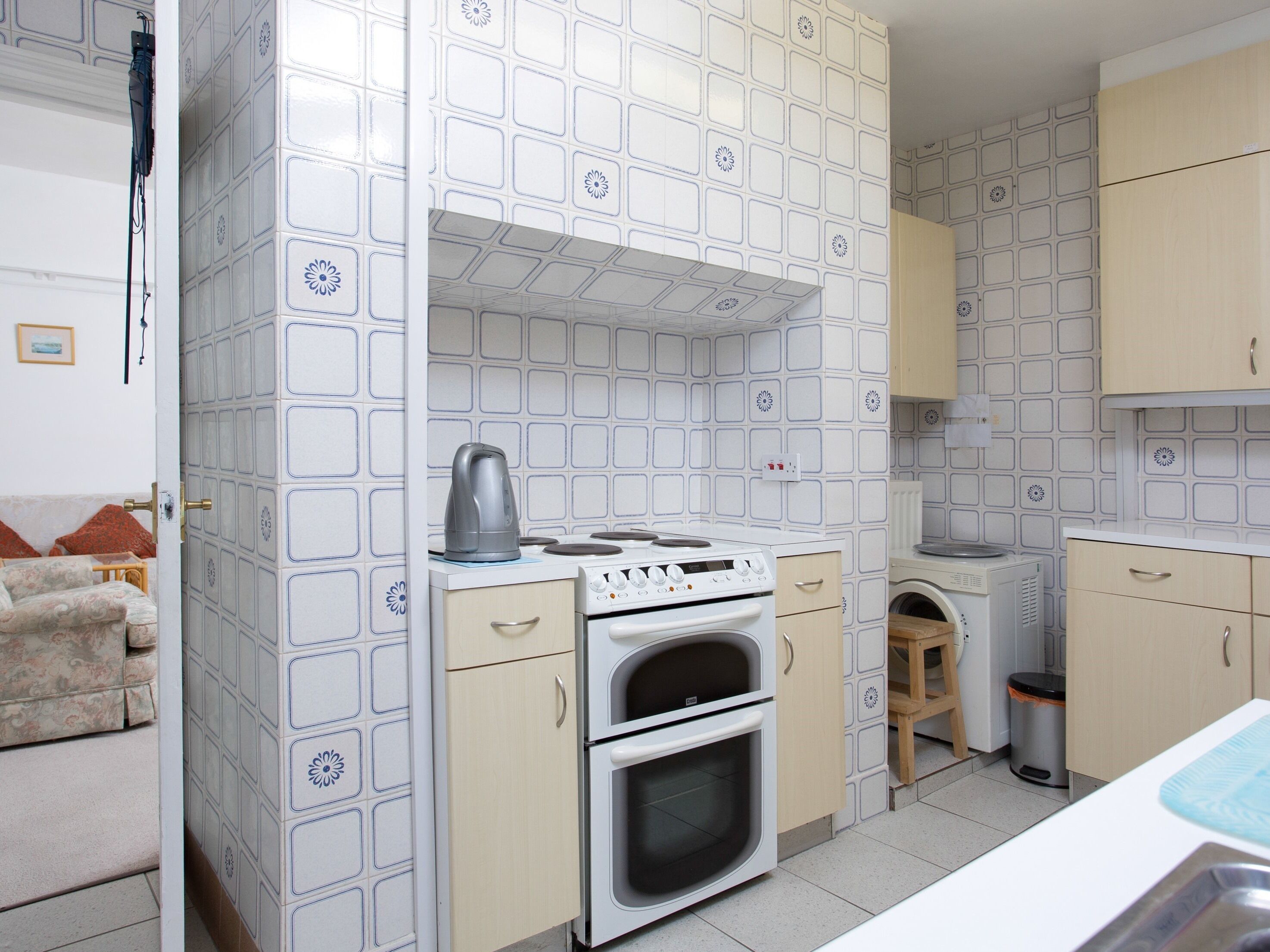 Una cocina compacta con estufa, horno y hervidor sobre la encimera.