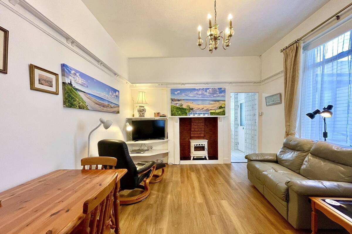 A cozy living room with a wooden dining table, a sofa, a television, and a fireplace.