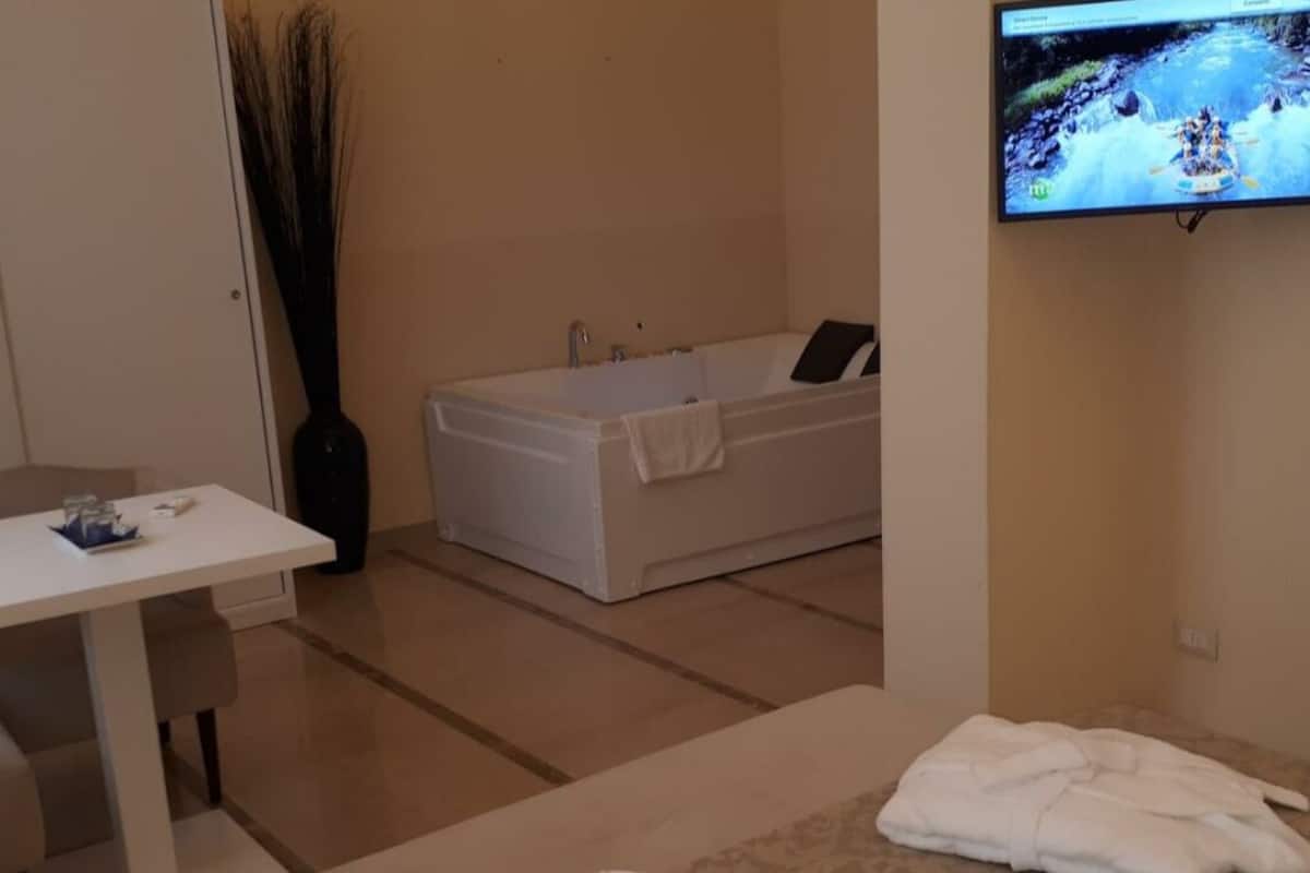 Un baño moderno con una bañera, un televisor montado en la pared y una mesa con toallas.