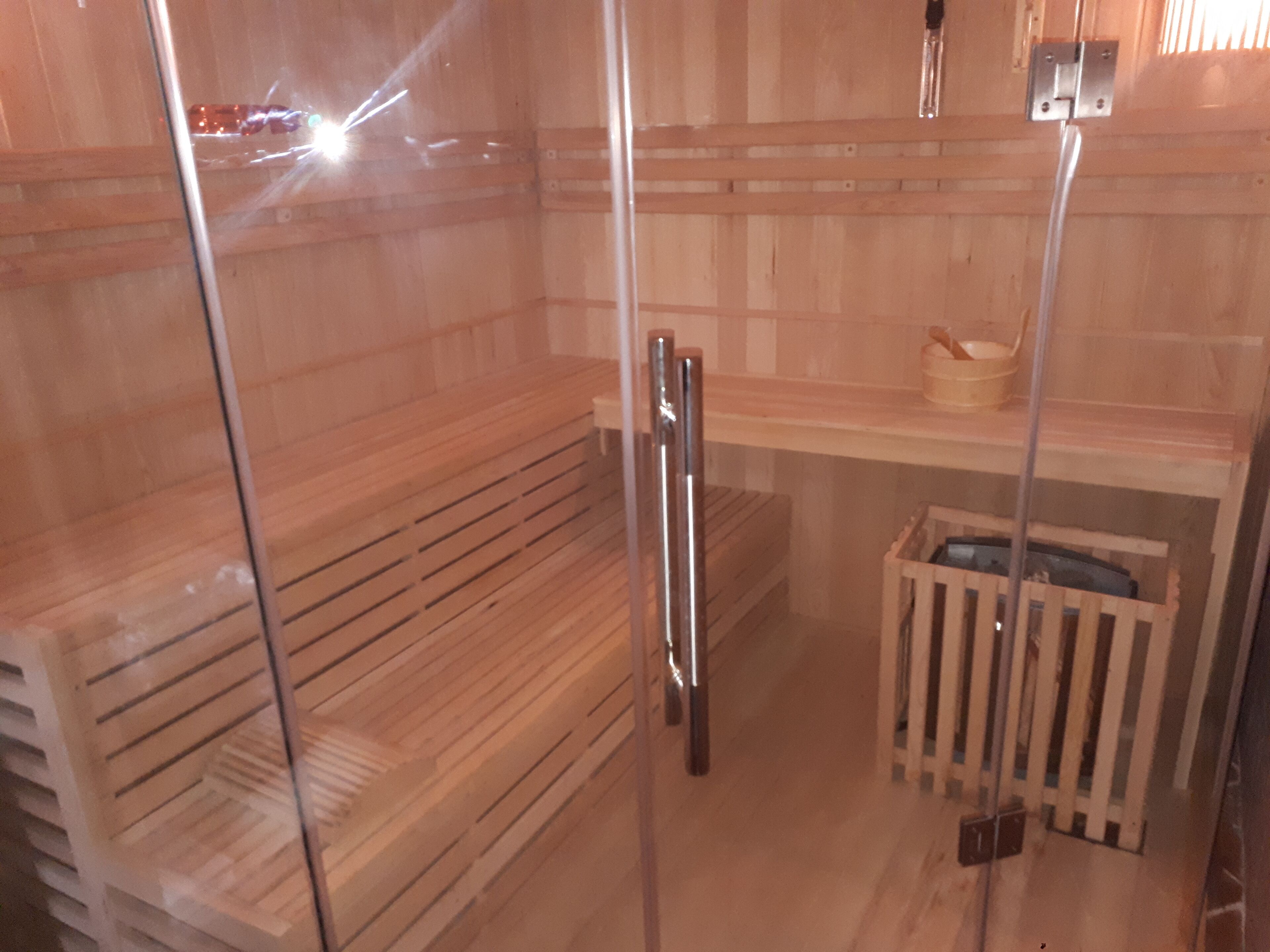 Sauna, jossa on puiset lauteet ja lasiovi.