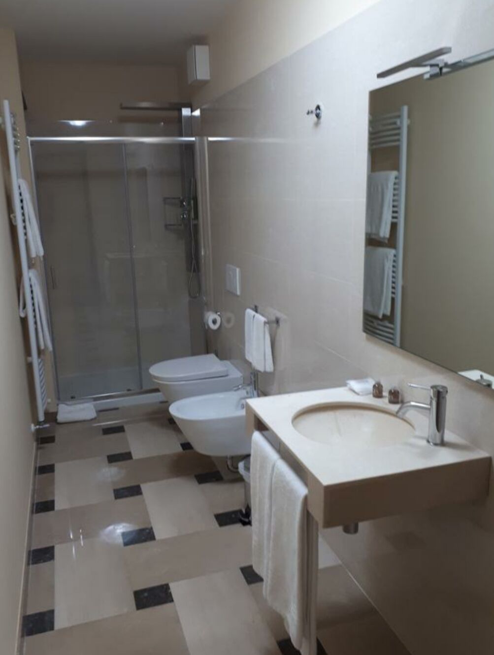 Un baño moderno con ducha de vidrio, inodoro y lavamanos con espejo.