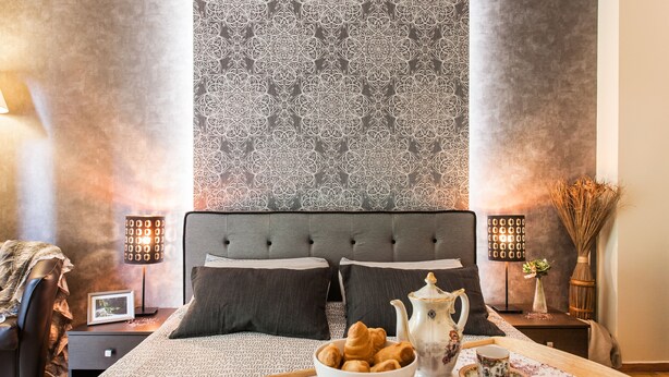 A neatly arranged bedroom with a large bed, bedside tables, a decorative wall, and a tray with breakfast items. - Beautiful Safe Apartment Near Centre (Athens)