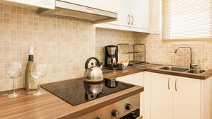 A modern kitchen with a gas stove, a kettle, a coffee maker, and a sink. - Beautiful Safe Apartment Near Centre (Athens)