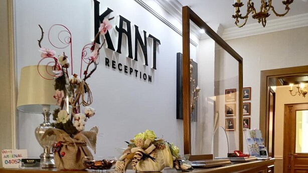 A reception desk with a sign reading "KANT RECEPTION," a chandelier, and a mirror above the desk. - Pensiunea Kant (Sibiu)