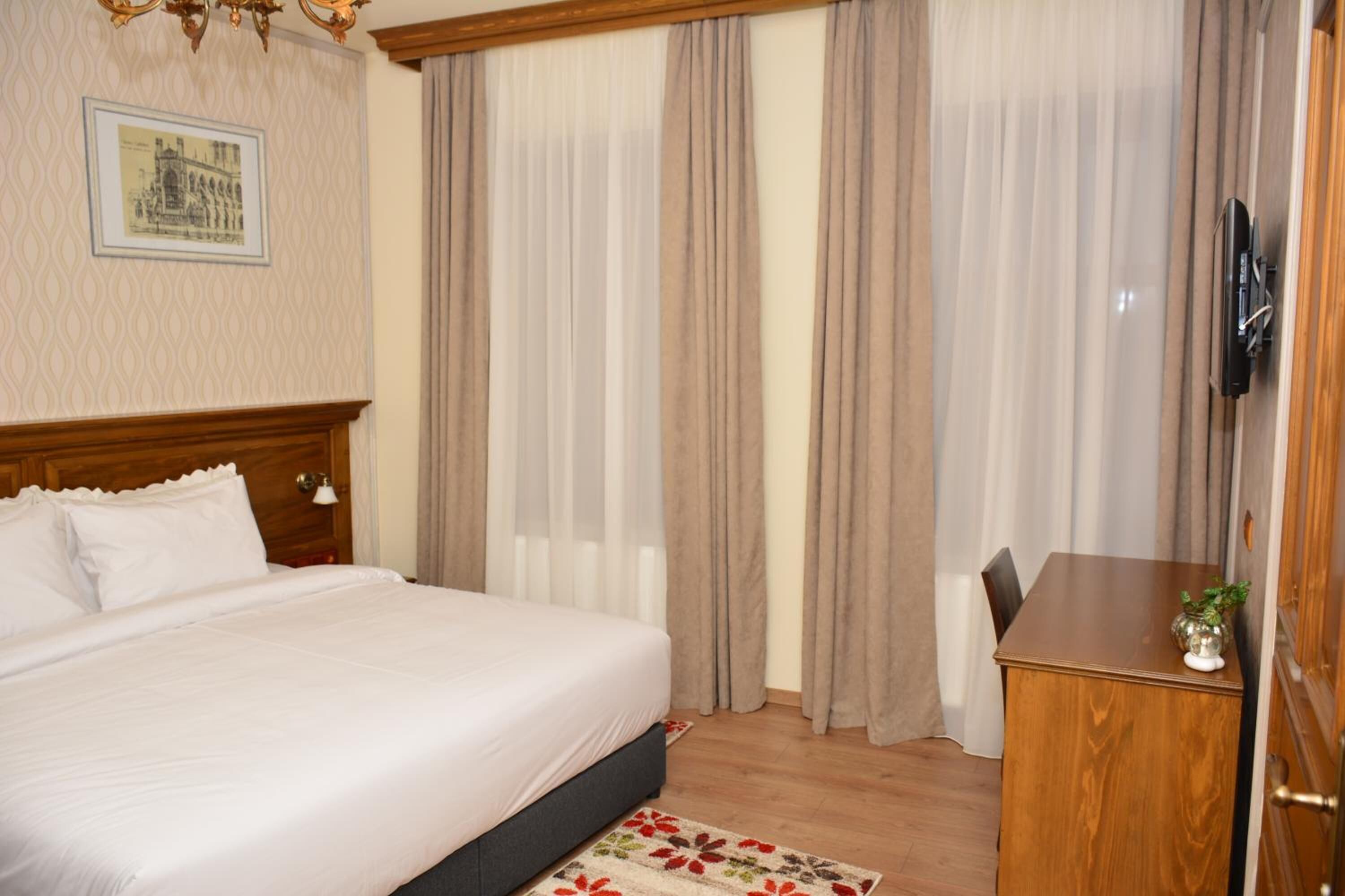 Una habitación de hotel con una cama grande, un escritorio de madera y una televisión.