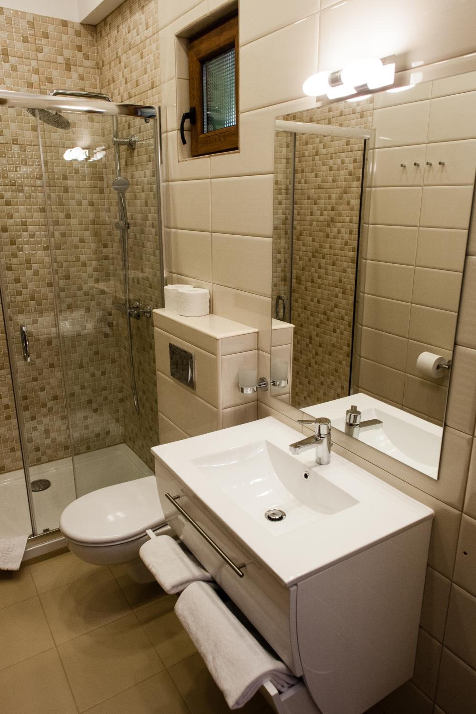 A modern bathroom with a glass-enclosed shower, a white sink, and a large mirror.