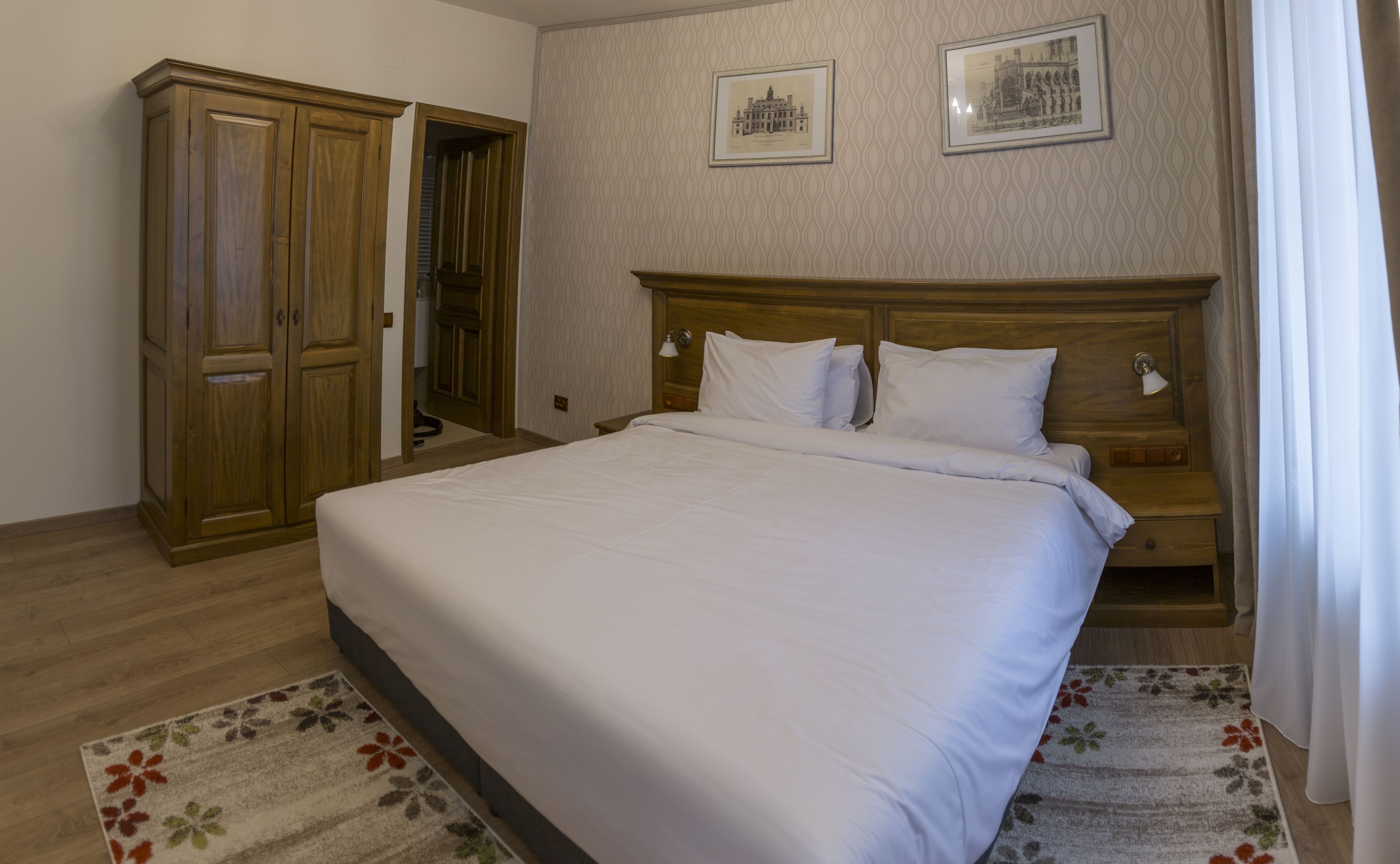 Un dormitorio con una cama grande, un armario de madera y dos cuadros enmarcados en la pared.