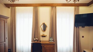 A hotel room with a wooden desk, a chair, a television, and a large mirror. - Pensiunea Kant (Sibiu)