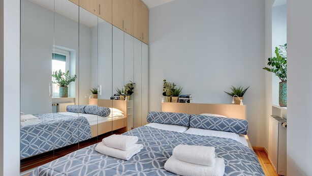 Un dormitorio moderno con una cama grande, un espejo y un armario de madera.