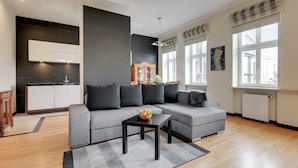 Una sala moderna con un sofá seccional gris, una mesita de centro negra y suelo de madera.