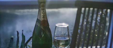 Eine Flasche Moët & Chandon Champagner und ein Glas auf einem Tisch, mit Blick auf ein Gewässer und Berge im Hintergrund.