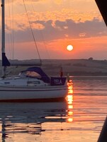 Un velero llamado "TELA" en aguas tranquilas durante el atardecer.